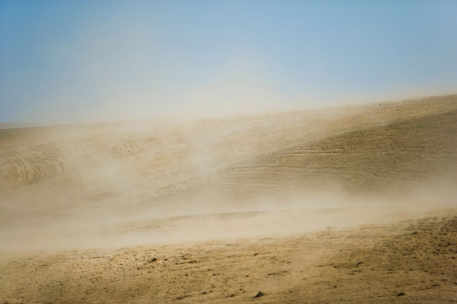Wind blowing dust across an arid landscape